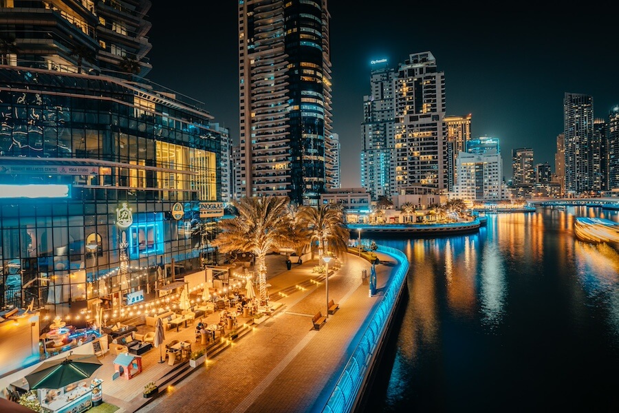 Večerní procházka po promenádě Dubai Marina s osvětlenými mrakodrapy a restauracemi. Tip na to, co dělat v Dubaji večer.