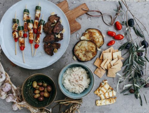 typická řecká jídla - olivy, souvlaki, hummus, rajčata a další zelenina na prostřeném stole