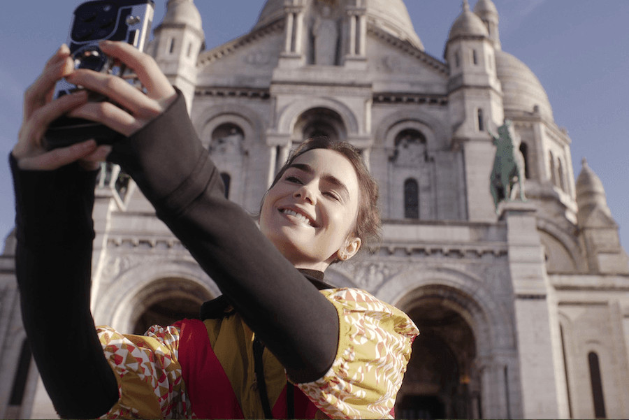 Hrdinka seriálu Emily in Paris, která si fotí selfie před bazilikou Sarce-Cœur v Paříži. Místo, kde se natáčela Emily in Paris