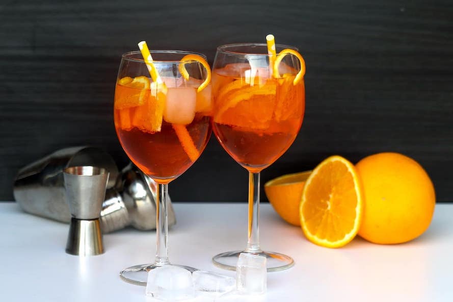 Alkoholický nápoj Aperol Spritz, dvě skleničky a pomeranč