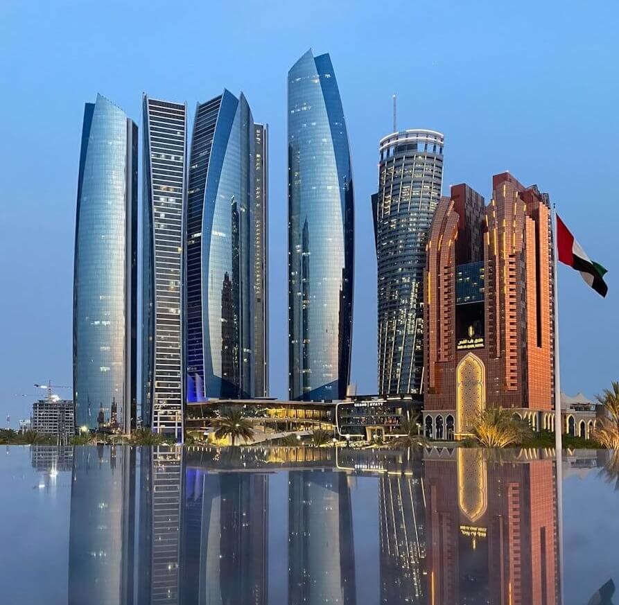 Komplex mrakodrapů Etihad Towers a vlajka SAE s dokonalým odrazem na vodní hladině. Místo, kde najdete Observation Deck at 300, top památku Abu Dhabi.
