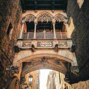Pohled zdola na slavný gotický mostek v uličce Carrer del Bisbe, který je jedním z nejhezčích míst, co navštívit v Barceloně v Barri Gòtic.