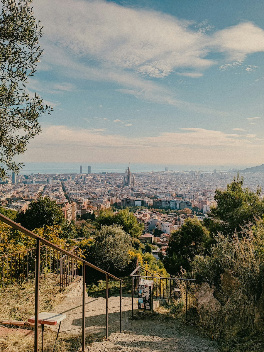 Úchvatný panoramatický výhled na Barcelonu ze schodů u Bunkers del Carmel s mořem a Sagrada Família v dálce. Tohle vyhlídkové místo je nutností, co vidět v Barceloně.