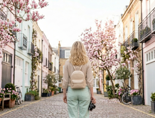 Blondýnka v béžovém svetru a mintových kalhotách s batohem prochází rozkvetlou uličkou St. Luke's Mews v Notting Hillu, Londýn. Nejfotogeničtější místa v Londýně.