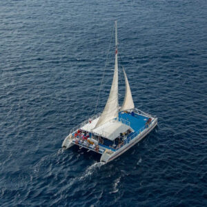 Bílý katamarán plující po hladině Středozemního moře u pobřeží Barcelony během vyhlídkové plavby. Jeden z tipů na zážitek v rámci Barcelona itineráře na 3-4 dny.