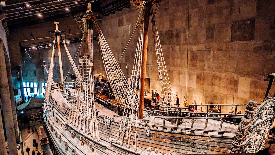 Majestátní válečná loď Vasa v expozici muzea zobrazená z boční perspektivy. Detailní pohled na historické lanoví a dřevěný trup nejnavštěvovanější památky ve Švédsku.