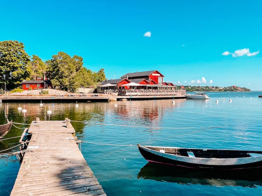 Stockholm archipelago: Pohled na jezero na ostrově Fjoderholmanna ve Švédsku. V popředí lodička u mola, v pozadí červený domek.