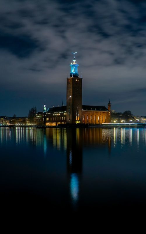 Noční Stockholm a tipy na to, co vidět ve Stockholmu po setmění: Osvětlená budova Radnice odrážející se na klidné hladině zálivu Riddarfjärden.
