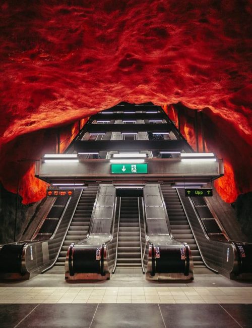 Dramatický červený strop stanice metra Solna centrum ve Stockholmu znázorňující západ slunce nad lesem, nejdelší umělecká galerie světa. Součást itineráře Stockholm na 3 dny.