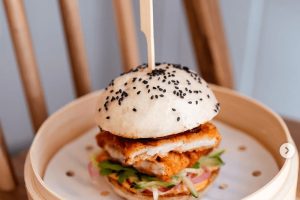 Burger na podnosu propíchlý špejlí. Kam na jídlo v Praze: Burger & Bublinky.