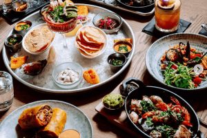 Stůl s talíři plnými mexických jídel - tortilly, zelenina, koktejly, Mexická restaurace, kam na jídlo v praze - mexická