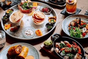 Stůl s talíři plnými mexických jídel - tortilly, zelenina, koktejly, Mexická restaurace, kam na jídlo v praze - mexická