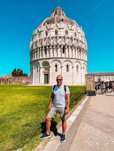 Muž stojící před monumentálním kruhovým Baptisteriem v Pise, průvodce Pisa za jeden den.