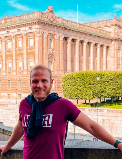 Mladý muž stojící před budovami švédského parlamentu ve Stockholmu