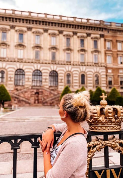 Královský palác ve Stockholmu, dívka s drdolem stojící před palácem s pohledem upřeným k paláci