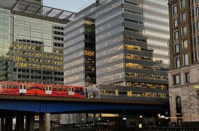 Pohled na koleje a jedoucí vlakovou soupravu DLR v Londýně v oblasti Canary Wharf
