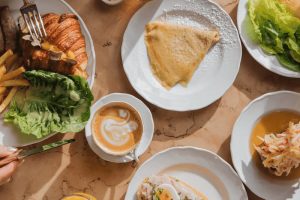 Bohatá snídaně v Café Savoy v Praze: Pohled shora na stůl s kávou, croissantem s lanýžem, slanou palačinkou a vejcem benedikt. Tip na skvělý brunch při hledání, kam na jídlo v Praze.
